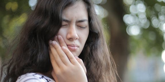 woman holding jaw due to jaw pain